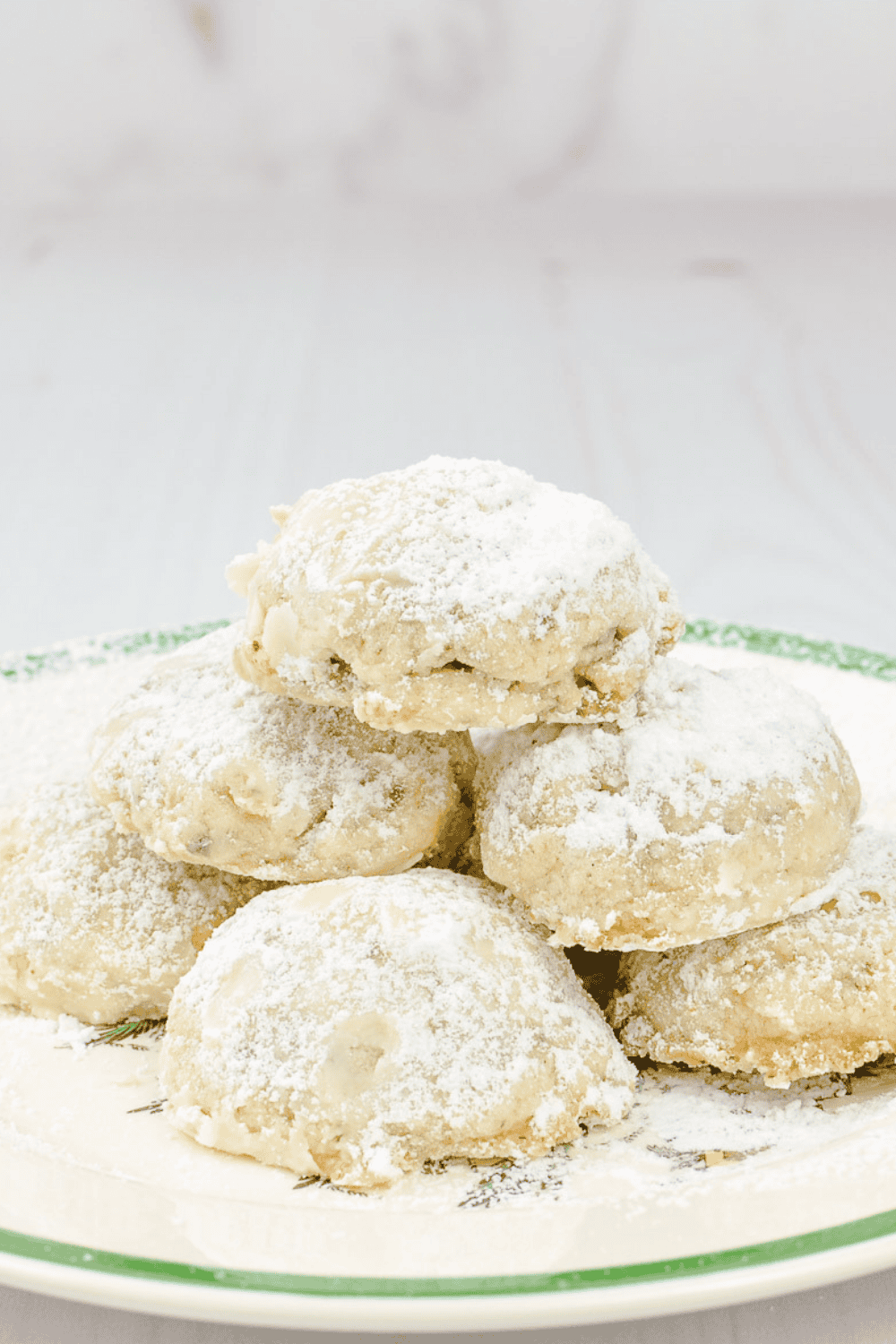 6 Melt In Your Mouth Snowball Cookies on a white plate with a green trim.