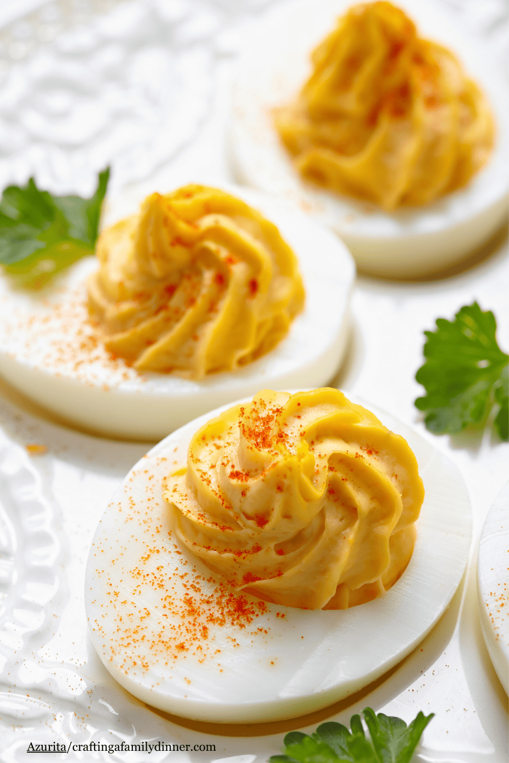 3 deviled eggs on a white platter with parsley.