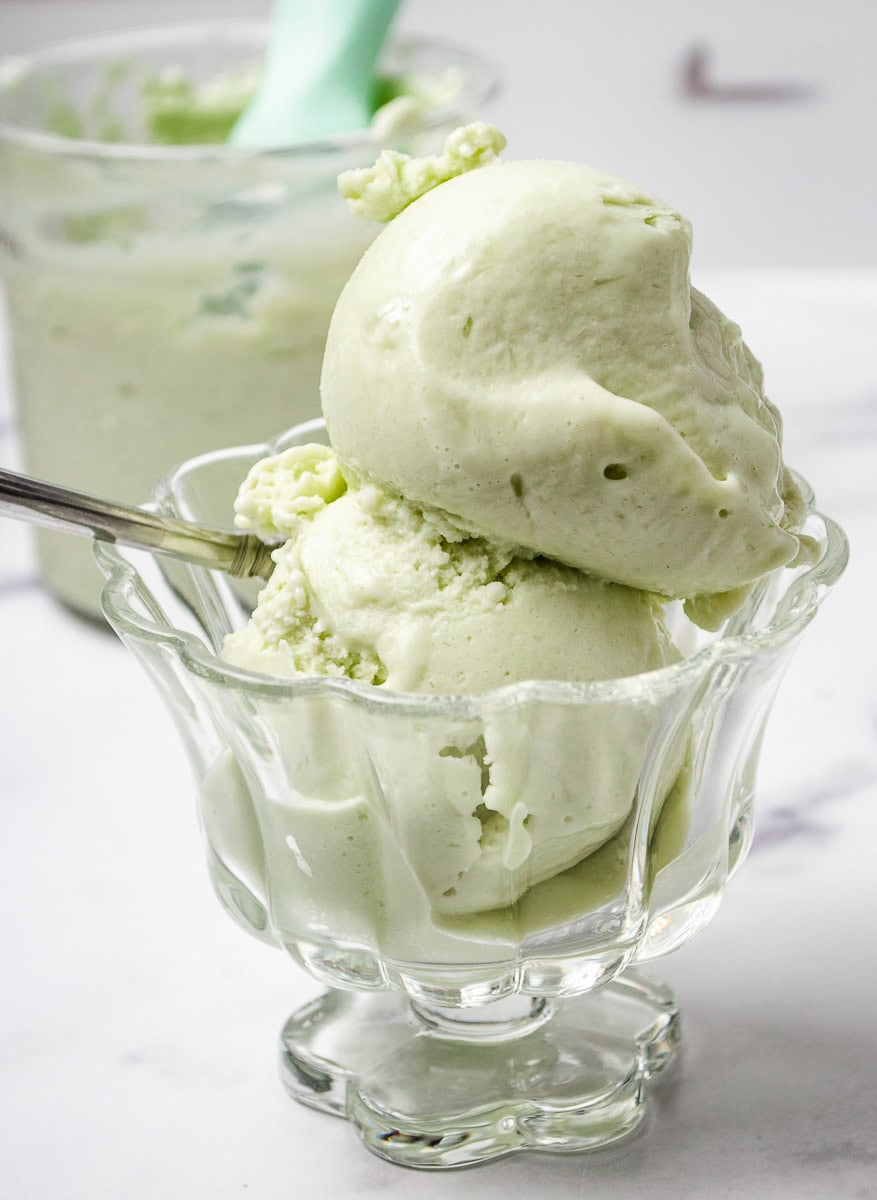 Two scoops of creamy Pistachio Ice Cream in a glass dish, made with sugar-free pudding, Pistachio Pudding, and blended in a Ninja Creami for a rich, high-protein dessert. This smooth and satisfying Protein Ice Cream is a delicious option for anyone searching for Healthy Ice Cream Recipes, Sugar Free Ice Cream, or a go-to Pistachio Ninja Creami Recipe.