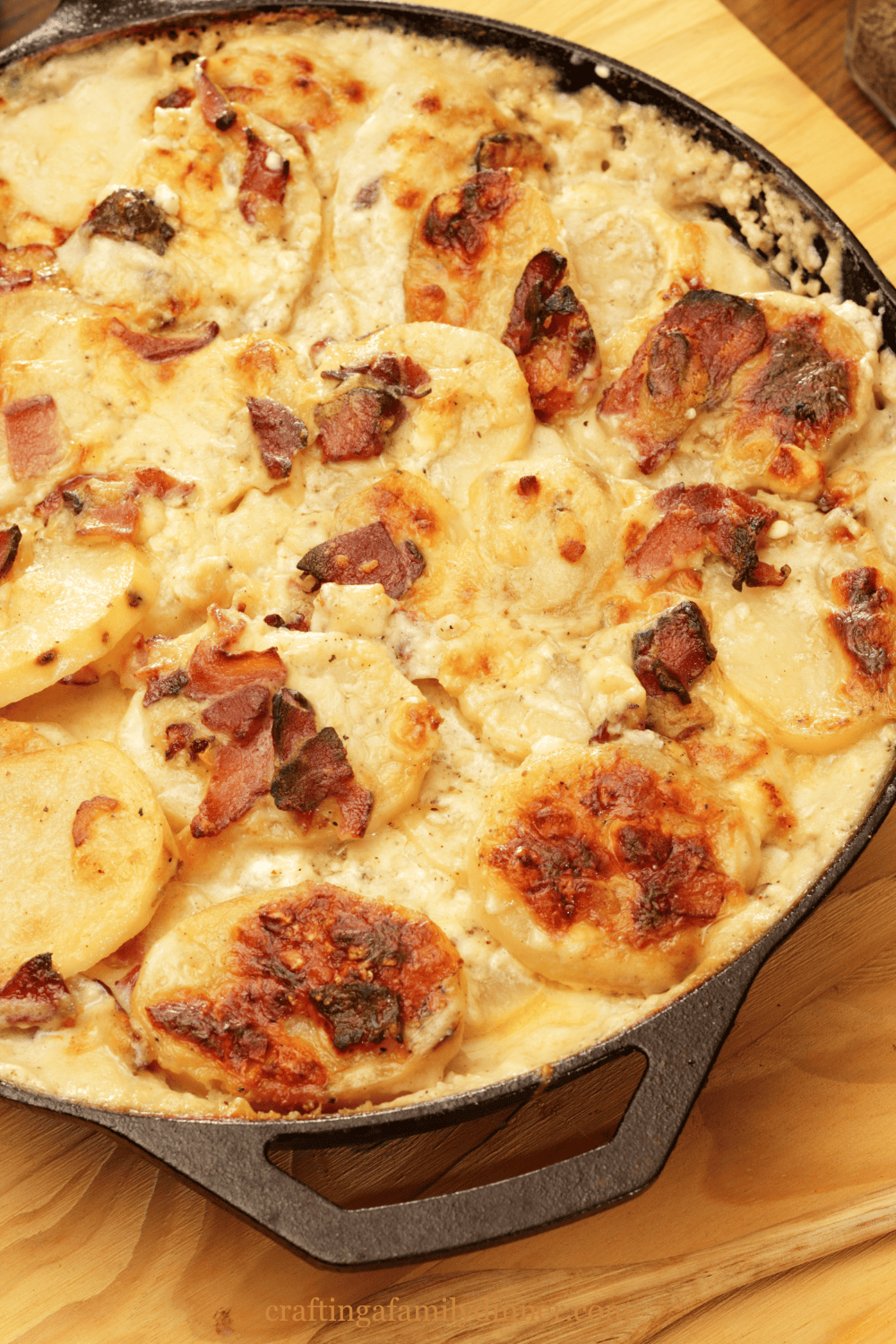 scalloped potatoes in a cast iron skillet on a wood counter