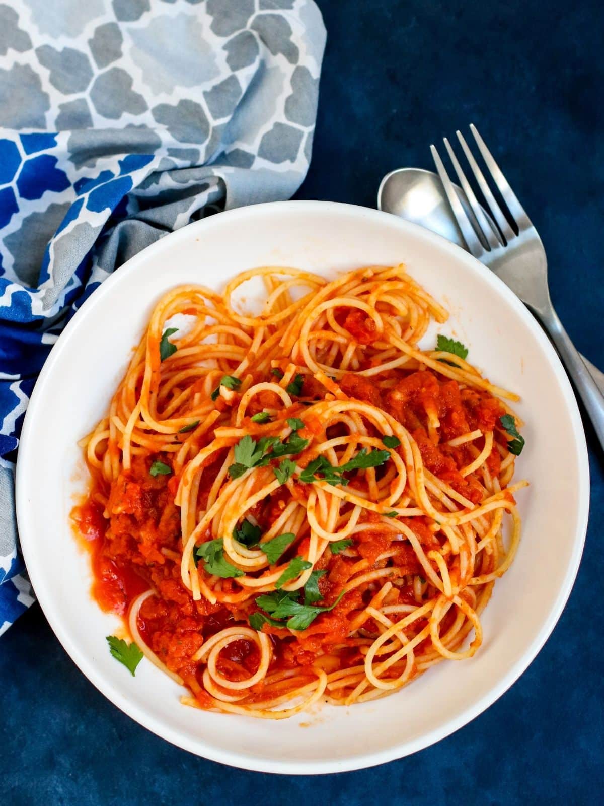 Spaghetti with pumpkin marinara sauce topped with fresh parsley served in a white bowl, a simple and cozy fall pasta dinner.