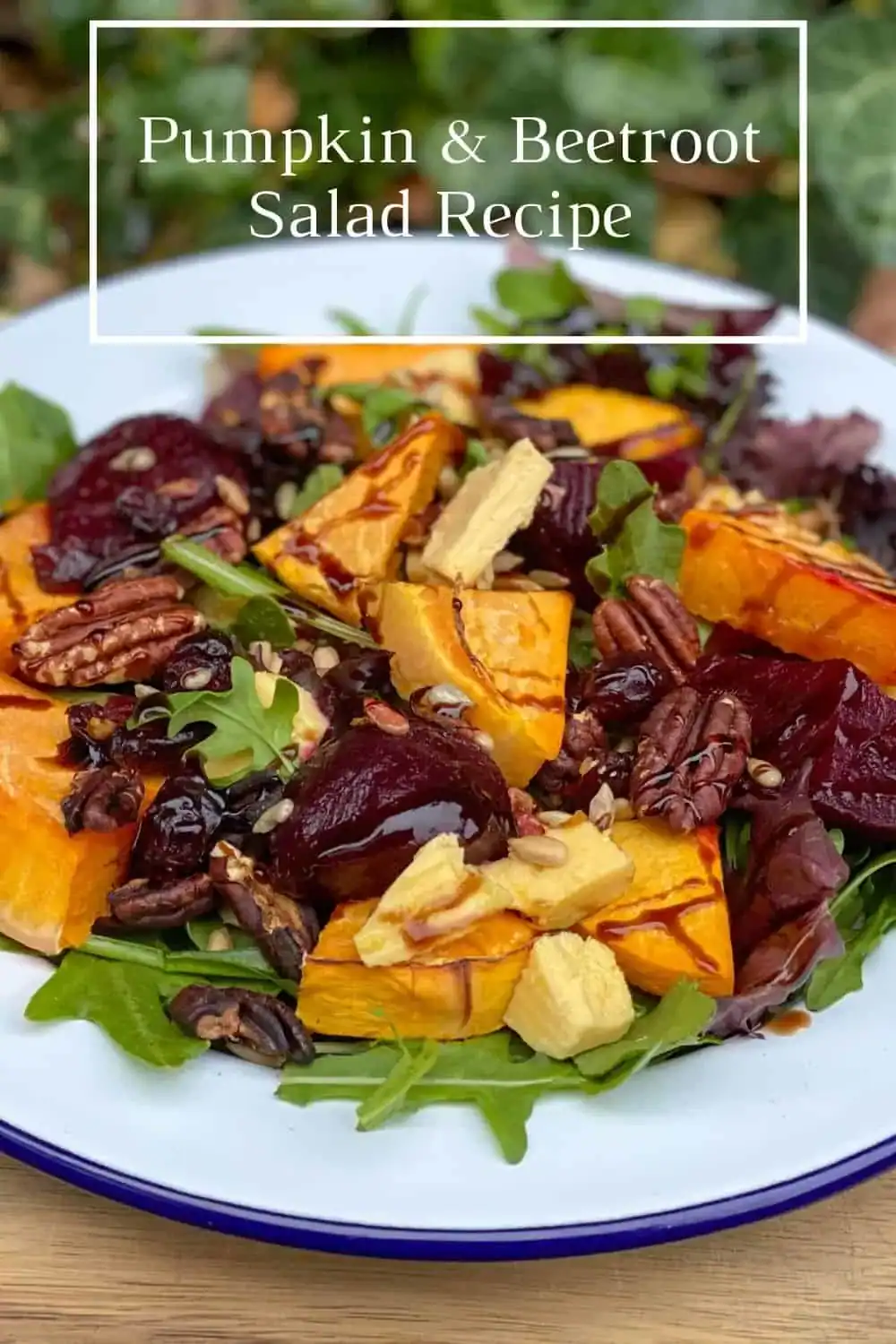 Colorful pumpkin beetroot salad with arugula, pecans, cheese, and balsamic drizzle served on a white plate.