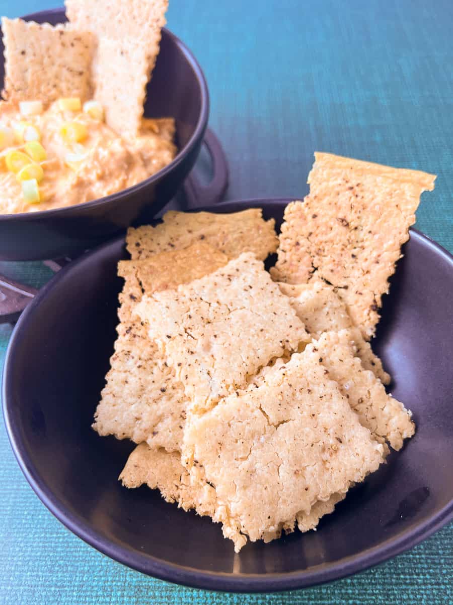 Crispy homemade sourdough crackers served with creamy buffalo chicken dip topped with green onions, the perfect pairing for game day food and easy buffalo chicken dip fans.