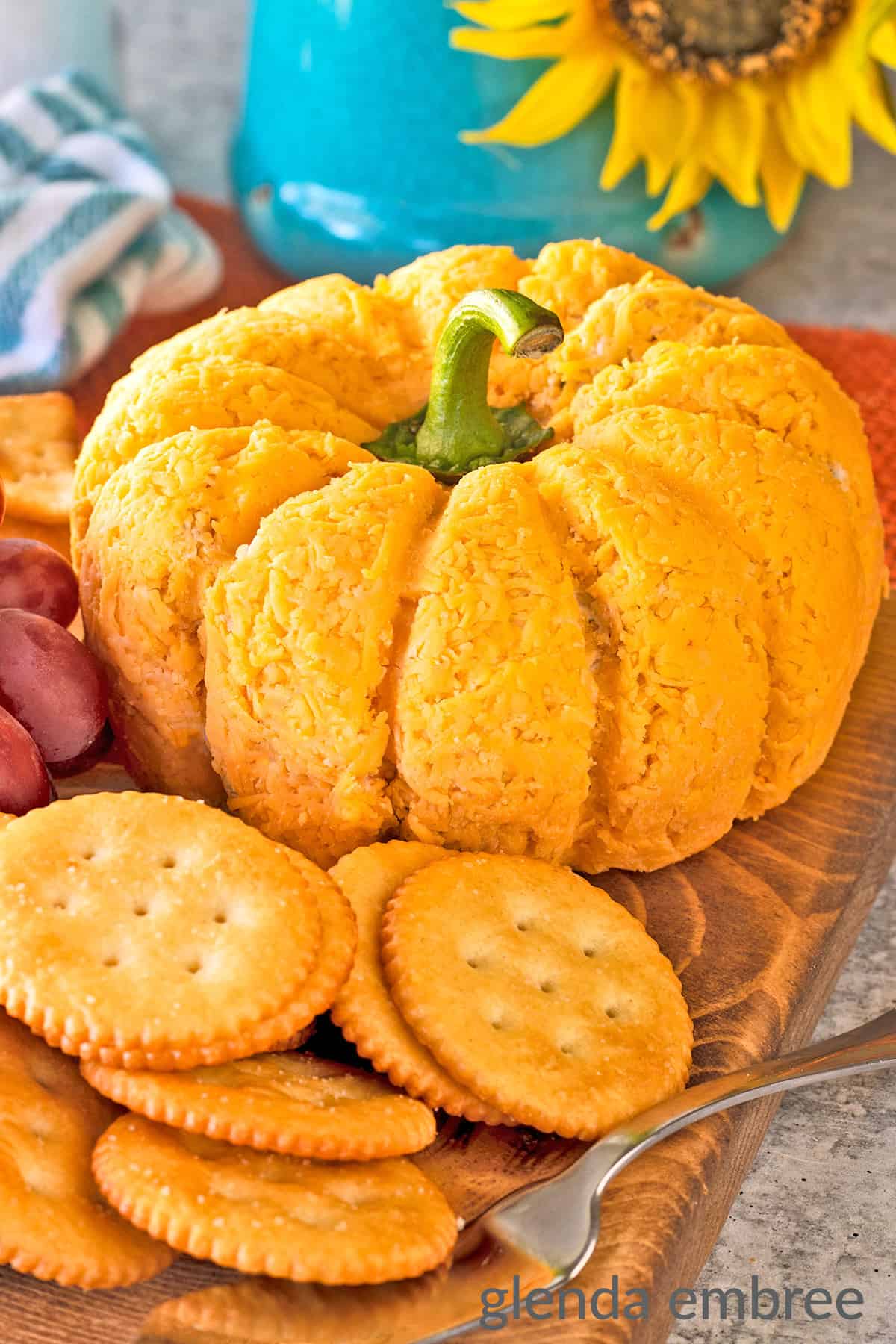 Bacon and Pineapple Cheese Ball shaped like a pumpkin, surrounded by crackersβan eye-catching option for cheese ball recipes and appetizers easy finger food.