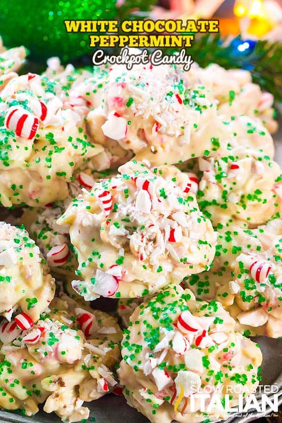 White chocolate peppermint crockpot candy piled on a tray, topped with crushed candy canes and green sugar sprinkles, with a bright and festive Christmas background.