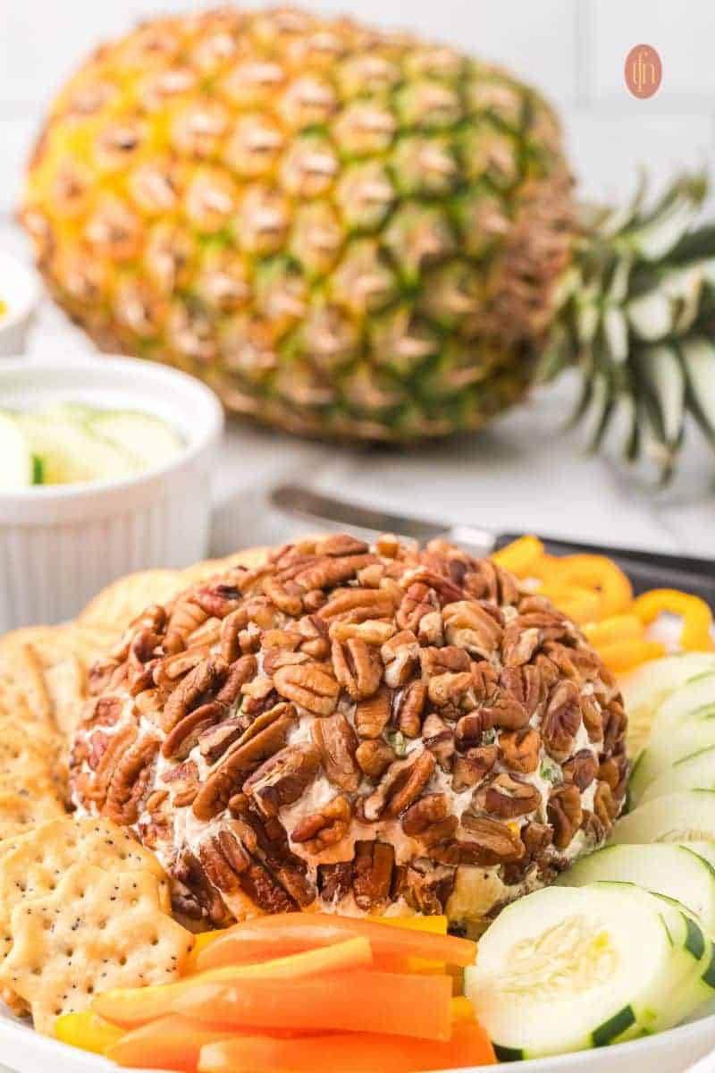 Pineapple Cheese Ball coated in pecans and served with cucumbers, carrots, and crackers β a sweet and savory hit among cheese ball recipes and easy appetizers for party.