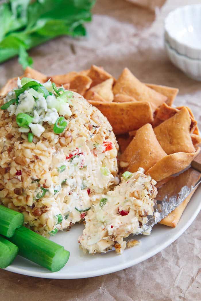 Buffalo Cheese Ball rolled in chopped nuts and topped with green onions and blue cheese, served with pita chips and celery β a spicy twist on cheese ball recipes and bold appetizers easy finger food.