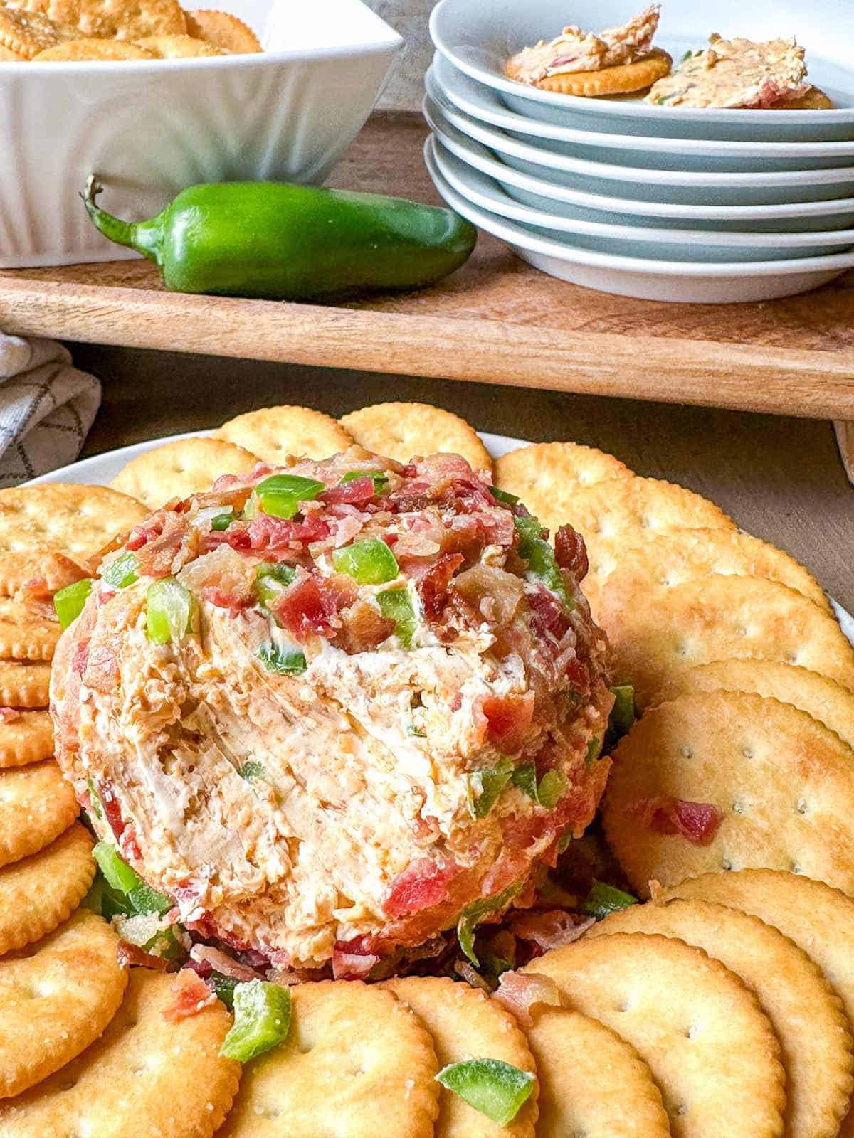 Jalapeno Popper Cheese Ball with bacon and green peppers, surrounded by crackers β a spicy and creamy favorite for cheese ball recipes and bold appetizers for party.