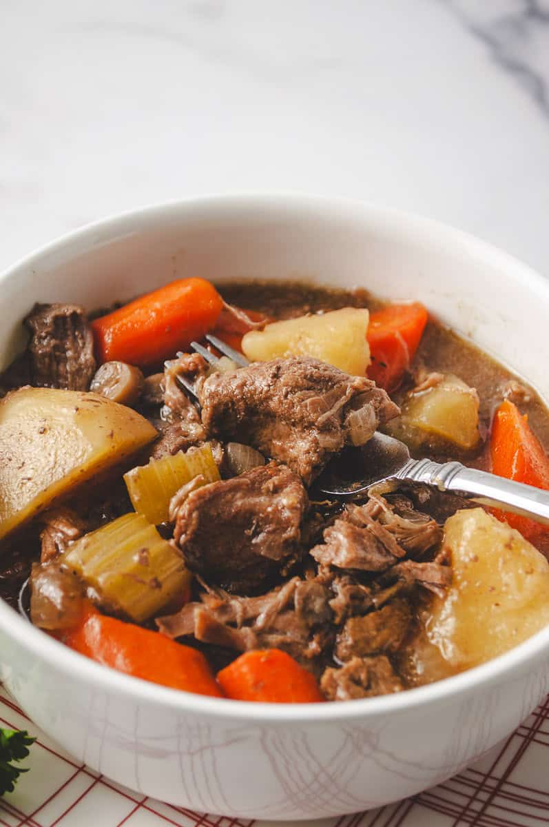 Close-up of slow cooker beef stew with tender beef chunks, carrots, potatoes, celery, and mushrooms in a rich beef broth—hearty crockpot recipe with deep flavor and classic comfort food appeal.