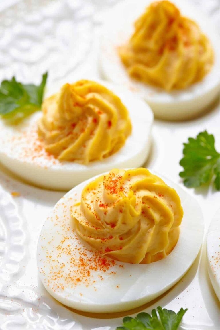 3 deviled eggs on a white plate with parsley