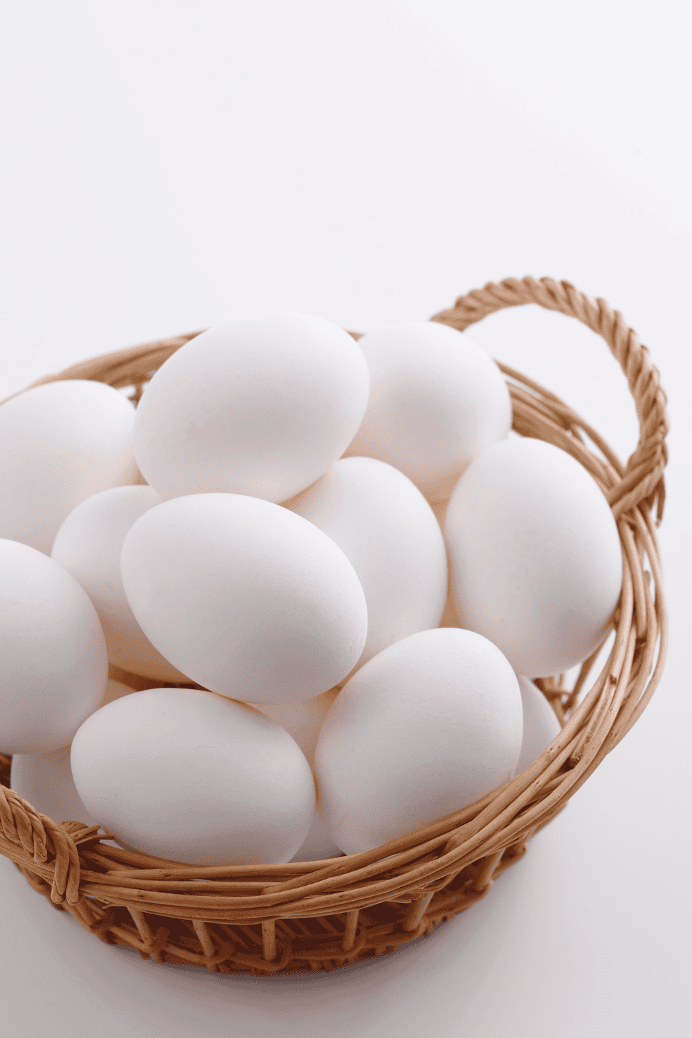 a dozen hard boiled eggs in a wicker basket on a white counter
