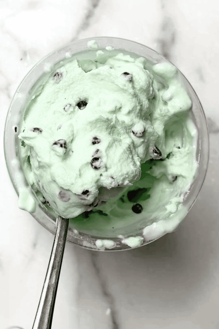 A close-up of creamy Ninja Creami Mint Chocolate Chip Ice Cream in a pint, loaded with mini chocolate chips. This high protein Ninja Creami recipe is low carb, fluffy, and perfect for a refreshing minty treat.