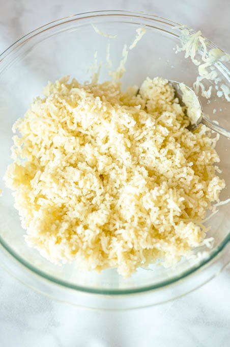 Riced potatoes in a glass mixing bowl before adding butter and milk