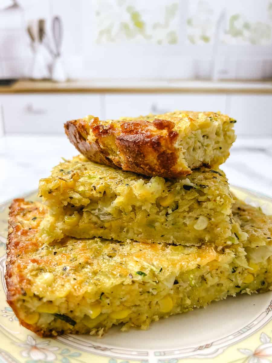 Three squares of garden zucchini cornbread casserole stacked to show the crisp browned top and how cleanly it slices