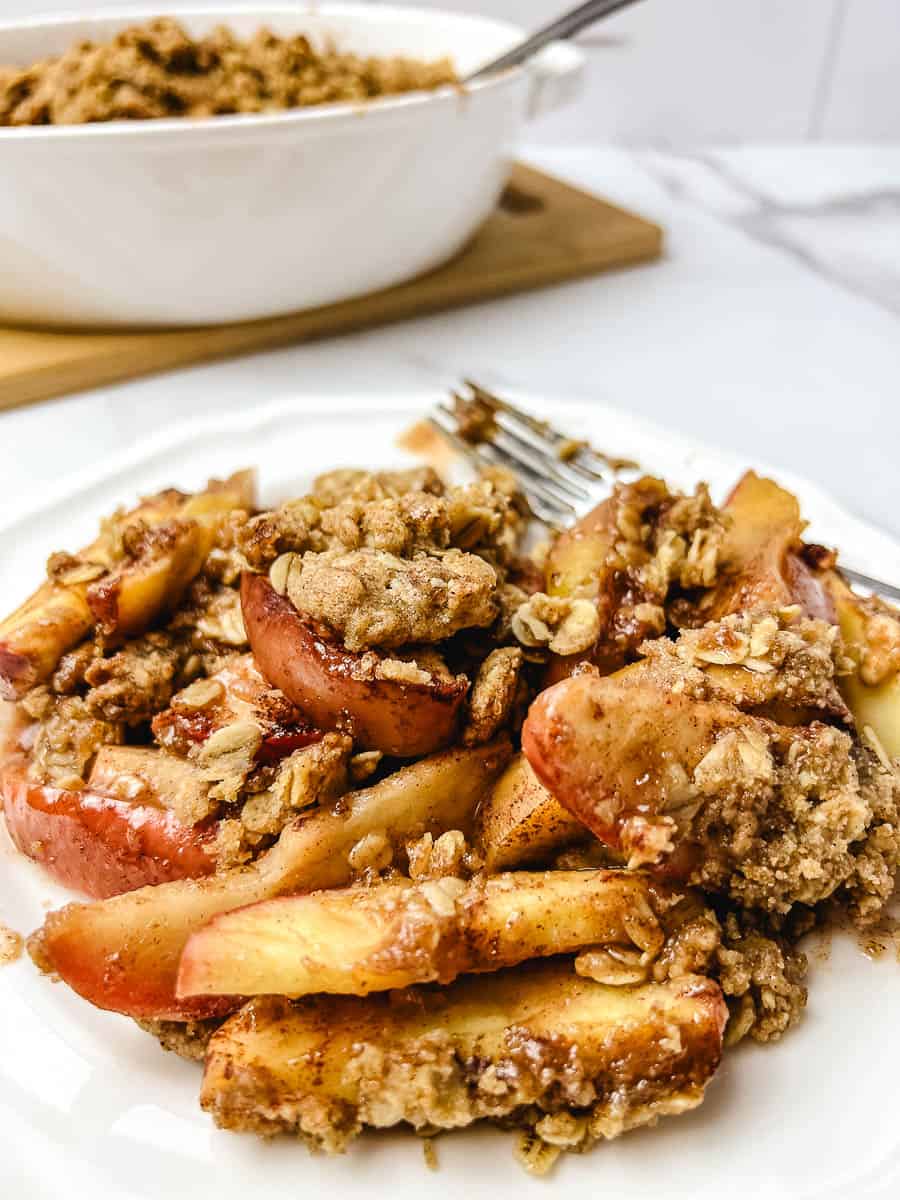 Warm homemade apple crisp with tender baked apples and a golden oat crumble topping, served on a white plate.