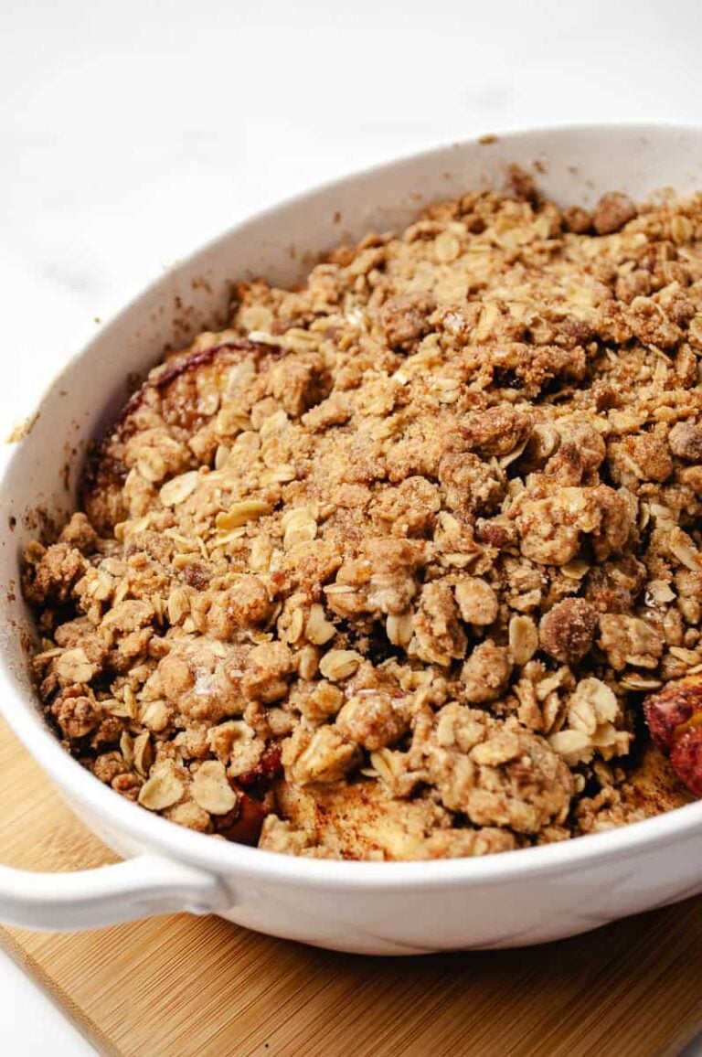 Freshly baked old-fashioned apple crisp with a golden oat crumble topping in a white baking dish.